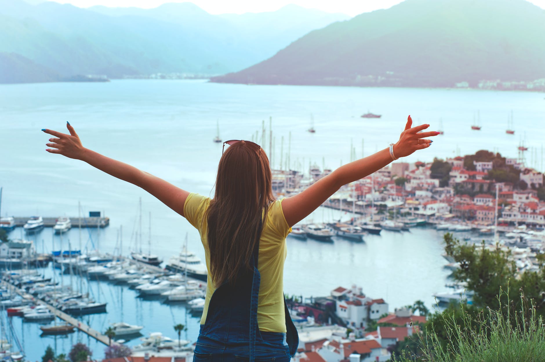 A women looking at the sea with her open arms. 
